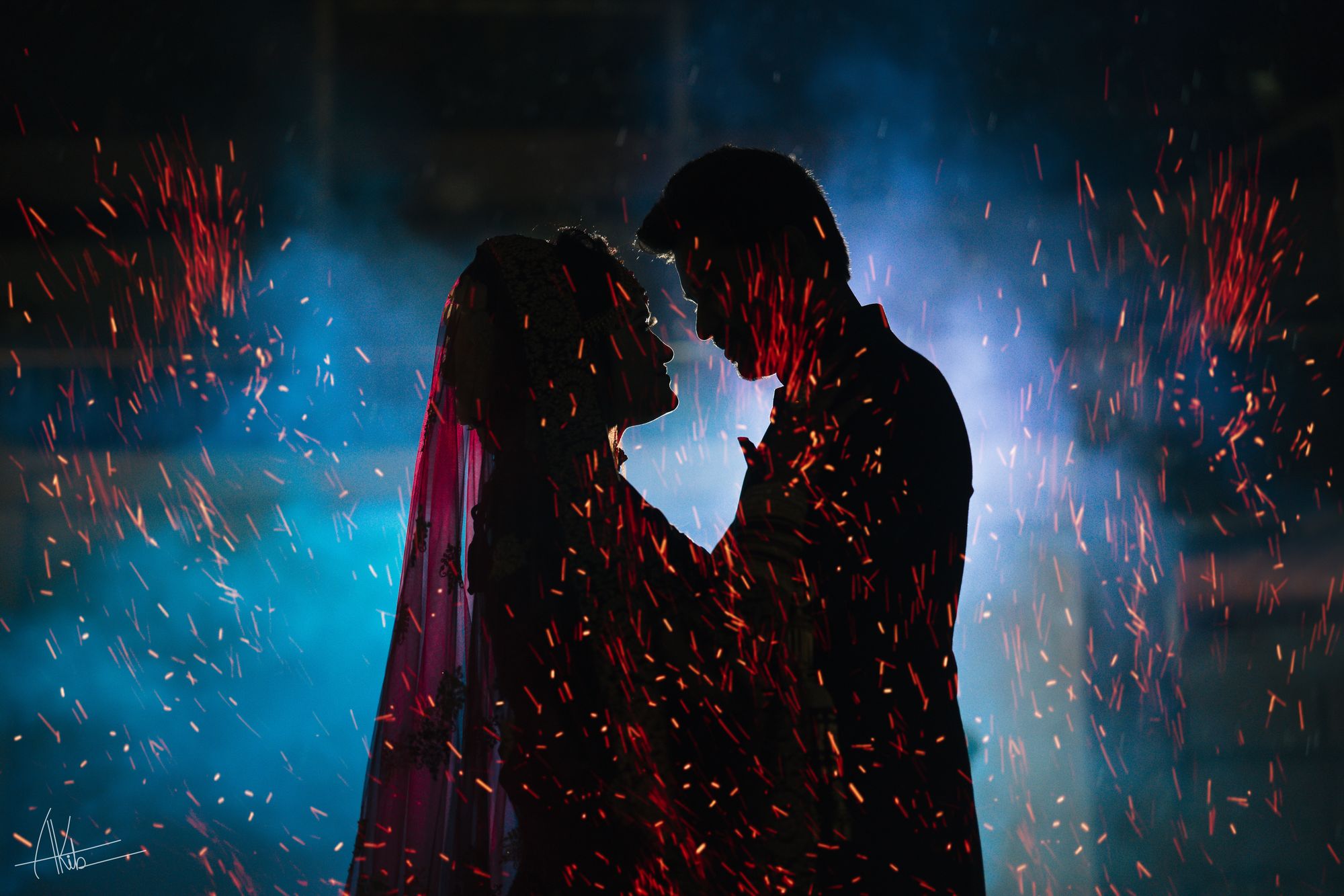 A couple silhouetted face to face in a shower of sparks