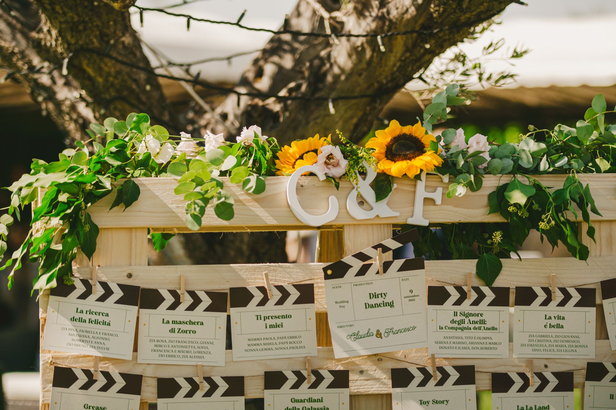 A rustic seating plan framed with sunflowers and greenery