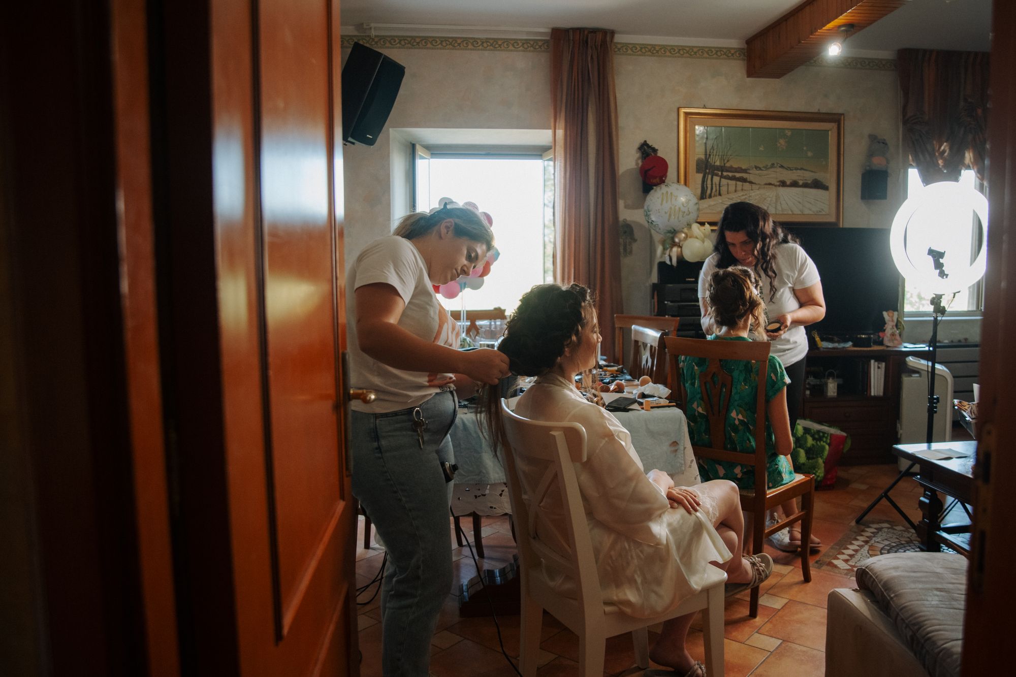 A bride having her makeup done in a busy family room